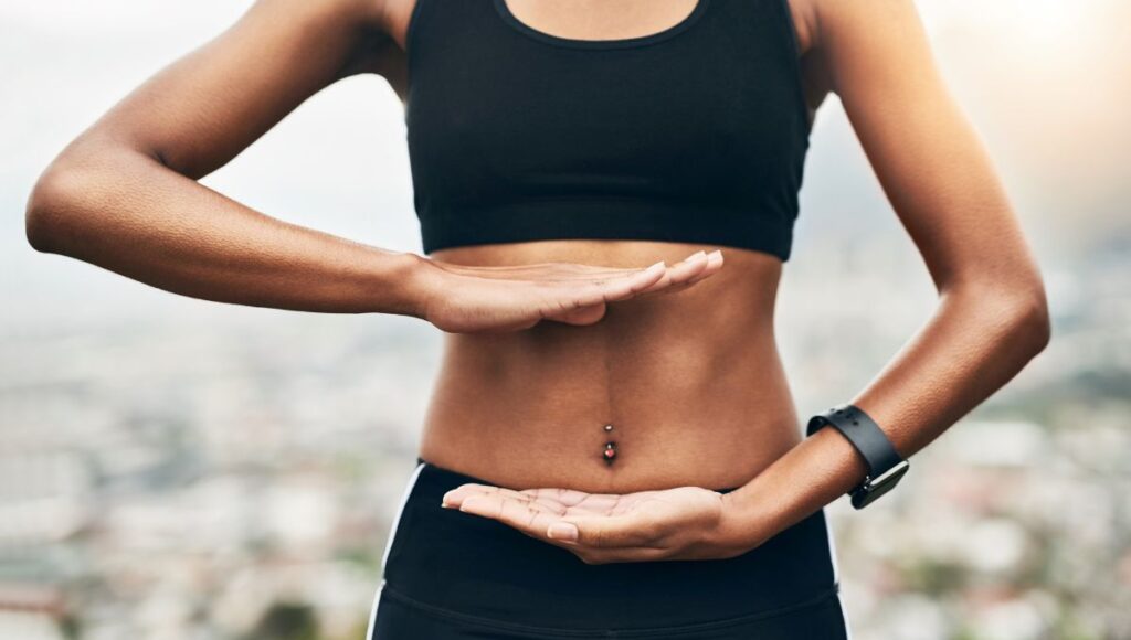 woman holding her hands over her core muscles 
