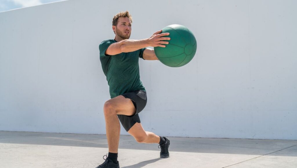 man twisting with a medicine ball in a lunge