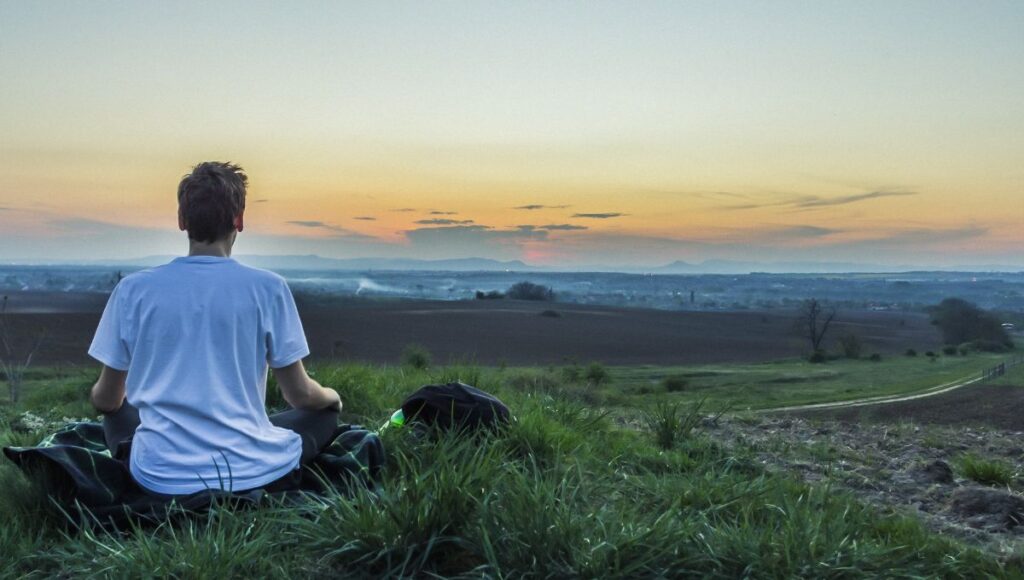 person sat meditating in a field 